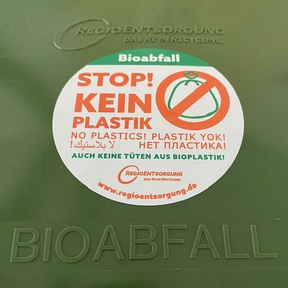Deckel von der grünen Biotonne mit einem Aufkleber "Stop! Kein Plastik"