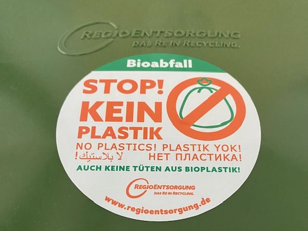 Deckel von der grünen Biotonne mit einem Aufkleber "Stop! Kein Plastik"
