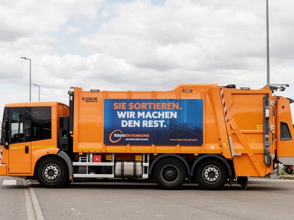 Pressmüllfahrzeug der RegioEntsorgung mit Banner "Sie sortieren. Wir machen den Rest"