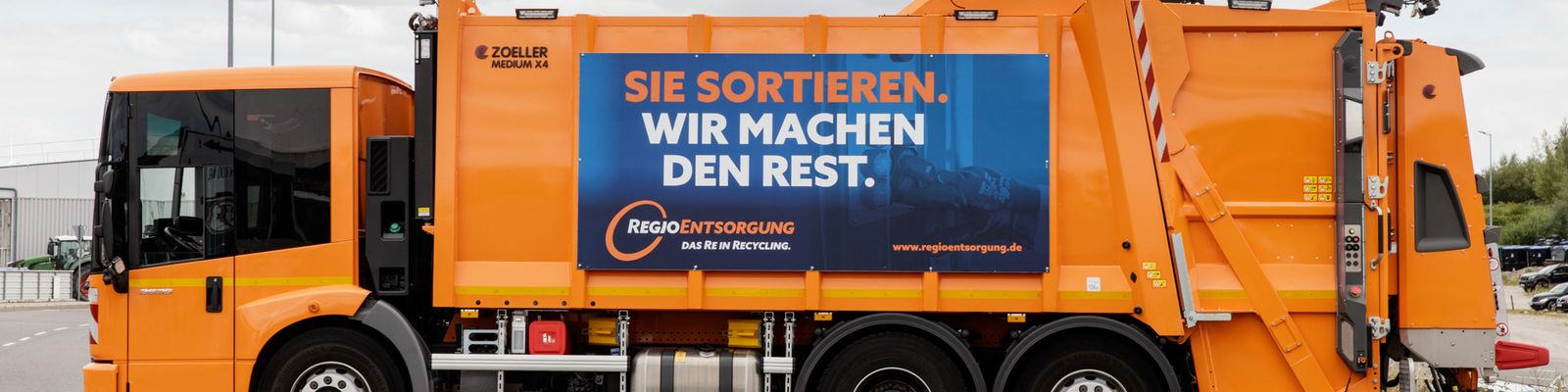 Pressmüllfahrzeug der RegioEntsorgung mit Banner "Sie sortieren. Wir machen den Rest"