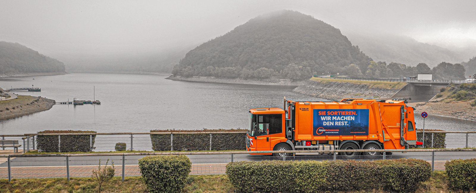 Panoramabild vom Pressmüllfahrzeug der RegioEntsorgung seitlich auf einer Brücke am Rursee
